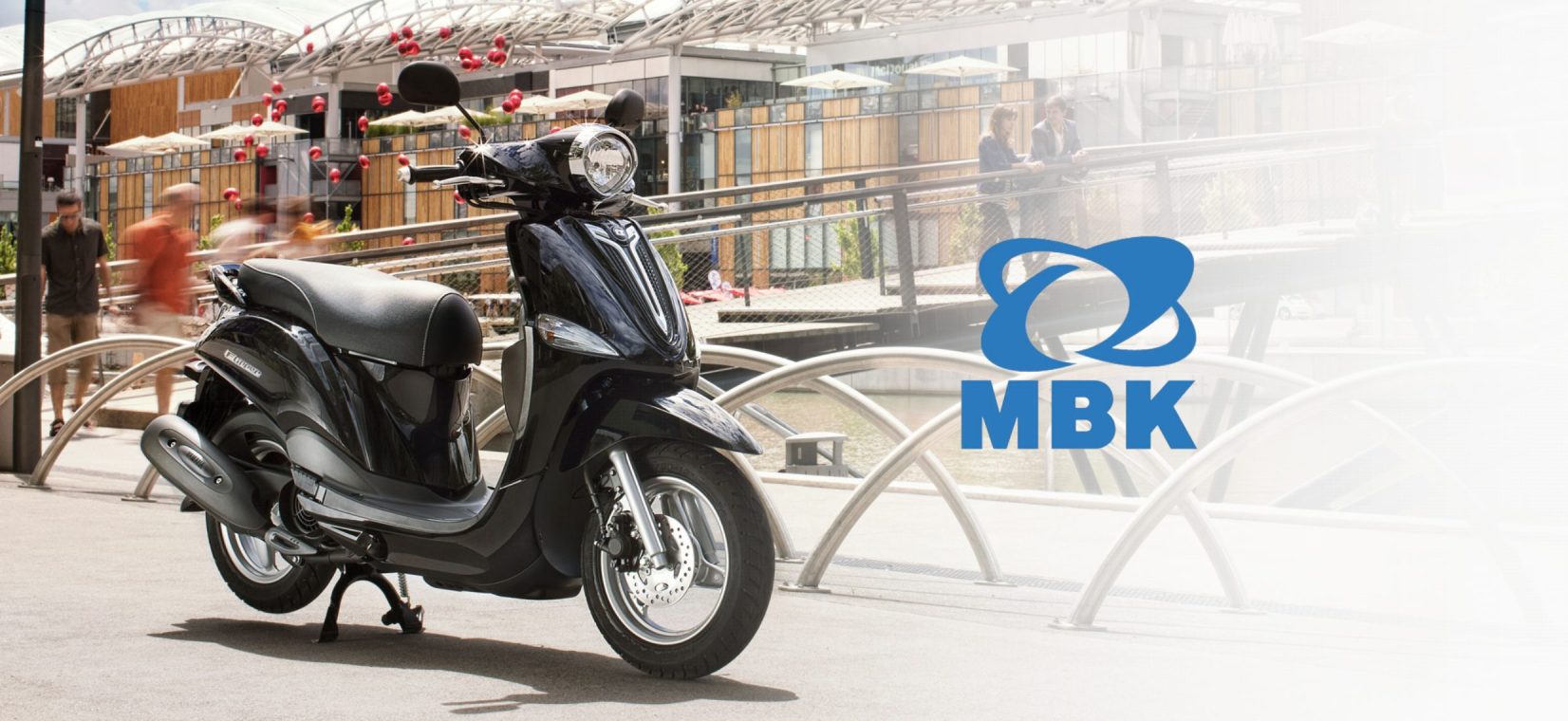 Visuel MBK : une moto dans un environnement de ville, avec un logo MBK