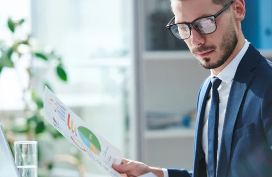 Directeur financier analysant un rapport de gestion avec graphiques – Parthena Consultant