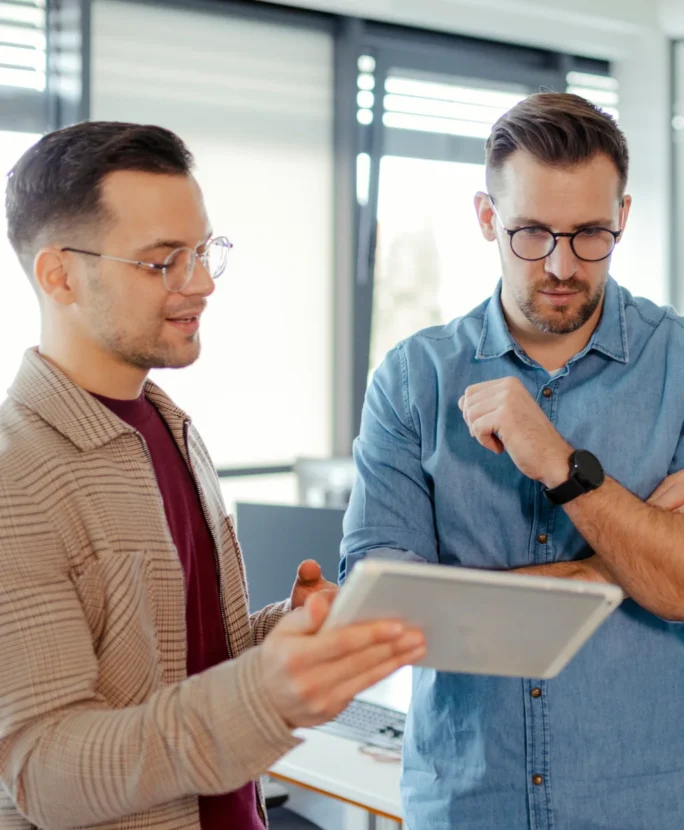 Deux responsables de fabrication regardant une tablette sur laquelle ils utilisent l'ERP Sage X3