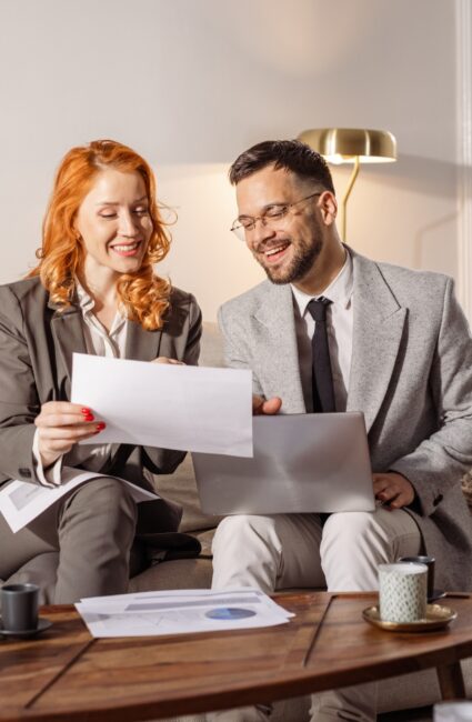 Deux professionnels analysent un document et des données sur un ordinateur portable.